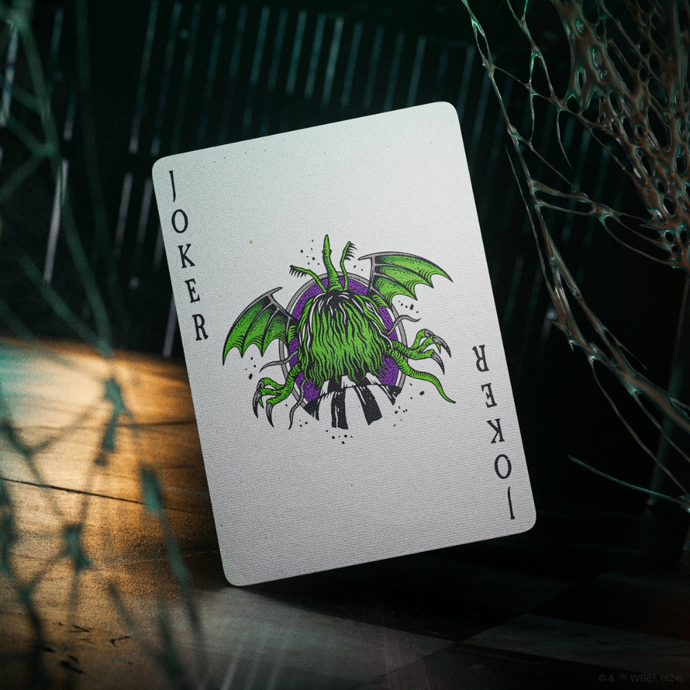 Joker card from a deck of Beetlejuice playing cards, in a creepy setting with sticky looking cobwebs
