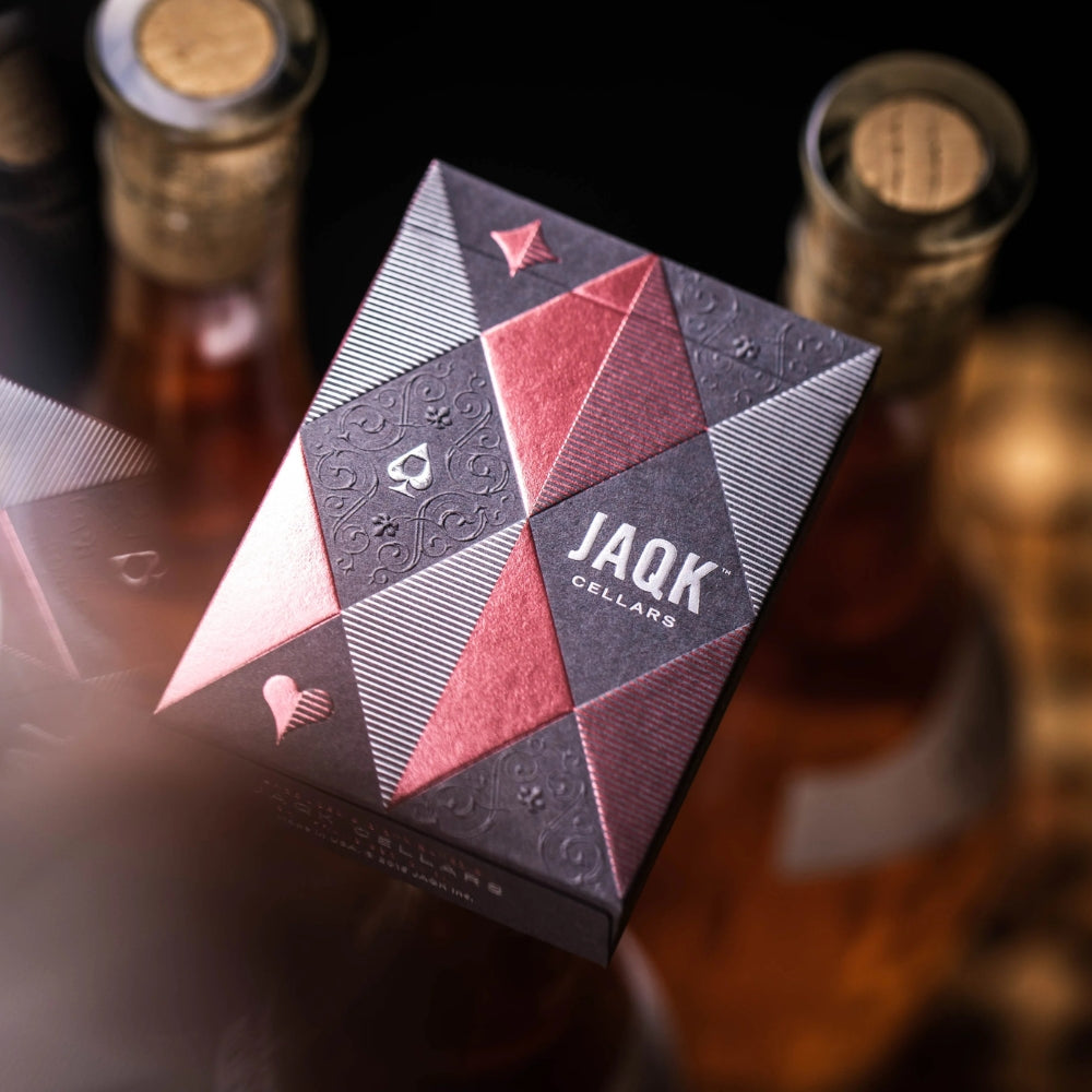 front of a deck of JAQK playing cards with bottles of win in the background