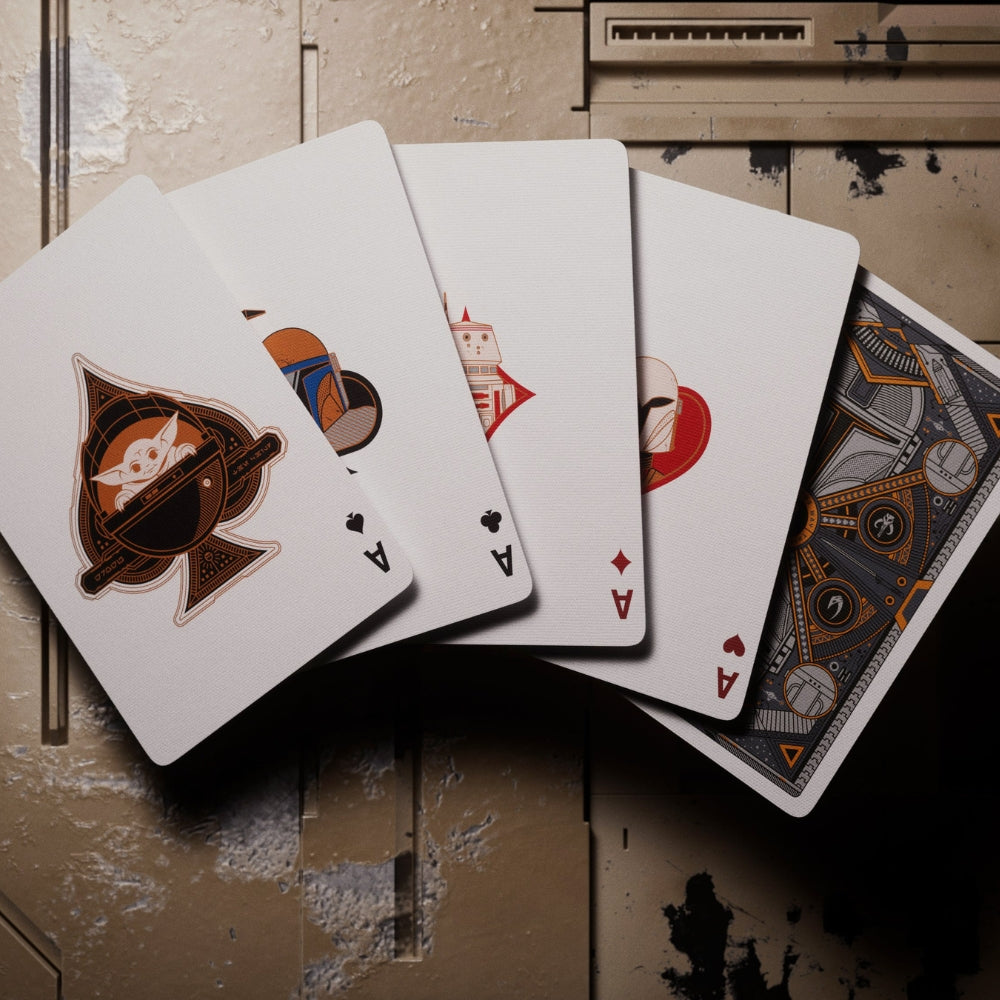 Fan of 4 aces cards laying on a tan, heavily damaged surface. The cards are taken from a set of Mandalorian playing cards