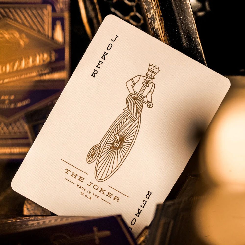 Joker card from a set of Purple monarch playing cards, featuring a line drawing of a man with a crown riding a pennyfarthing