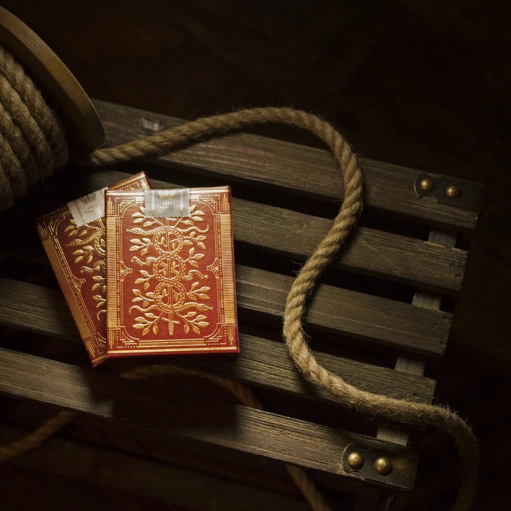 Two decks of red monarch playing cards on a slotted wooden surface.
