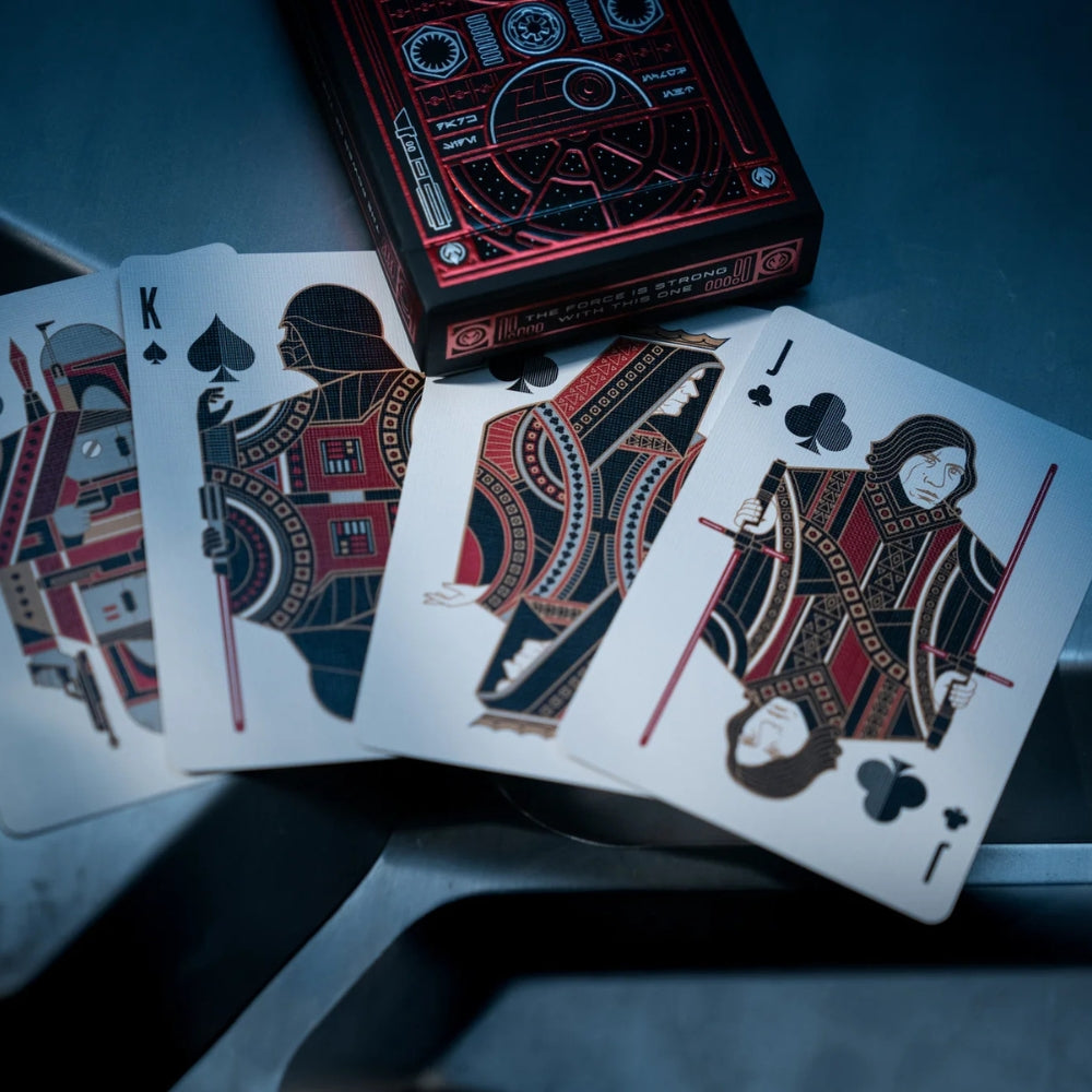 A fan of four face cards laying on a metal surface, with a deck box laying close by, all from a set of star wars playing cards
