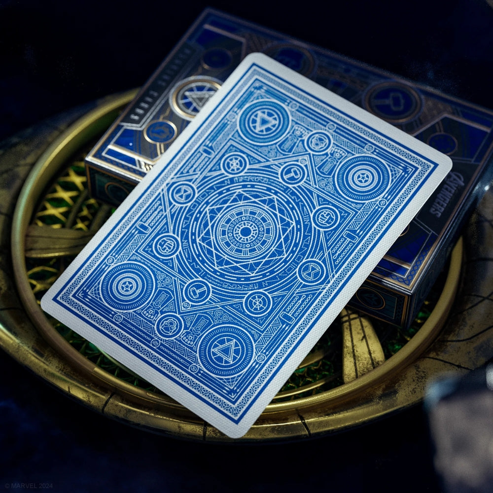 Facedown avengers playing card (blue edition), laying on a deck box and a gold item