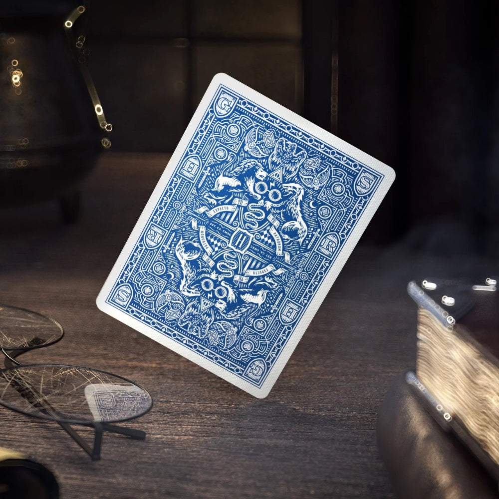 Picture of the back of the Ravenclaw Harry potter card on an old wooden desk, also features a pair of Savile Row Warwick styled glasses, a cauldron and two leather bound books.