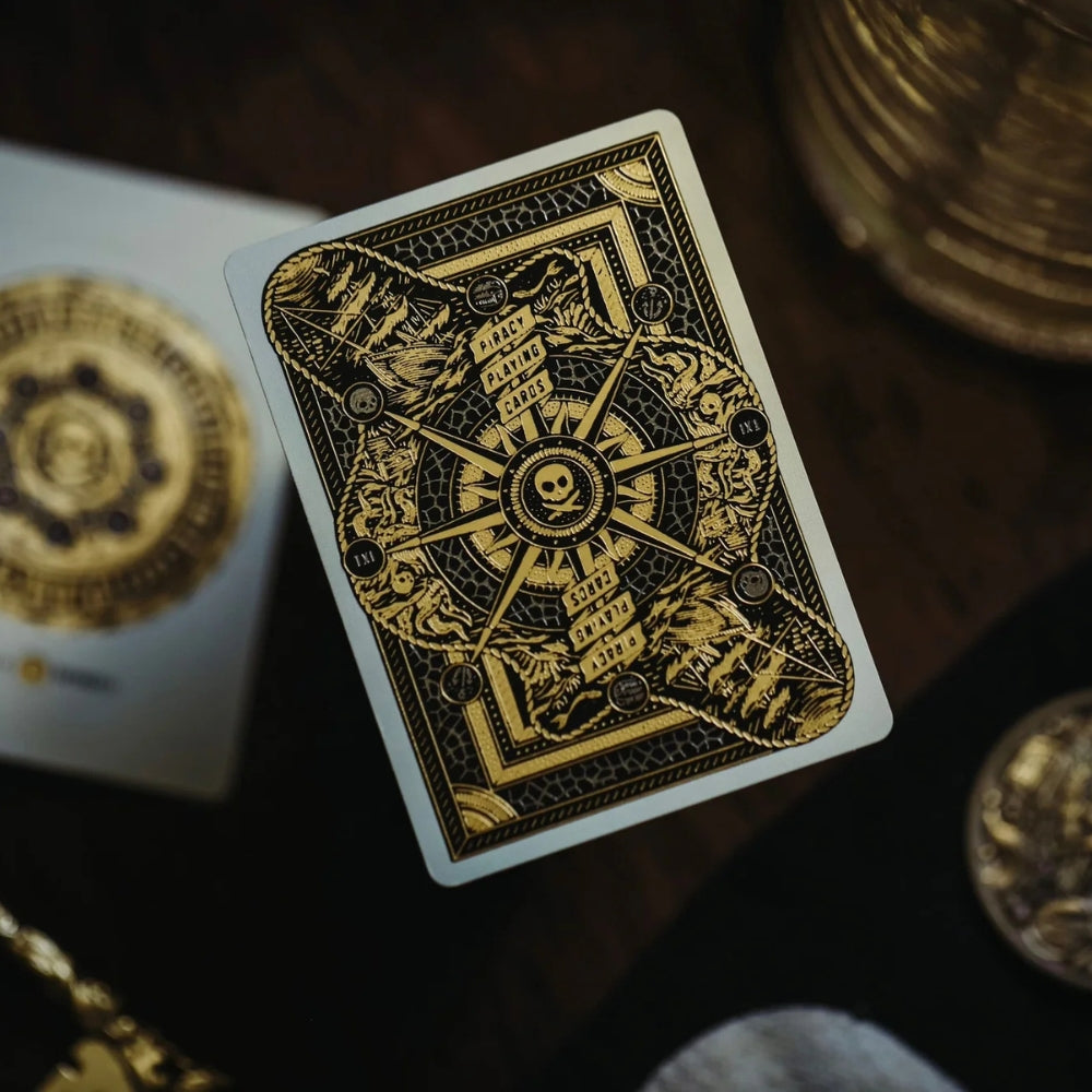 Back of a piracy playing card, laying on a deck, with a coin and drinking glass partially in the shot