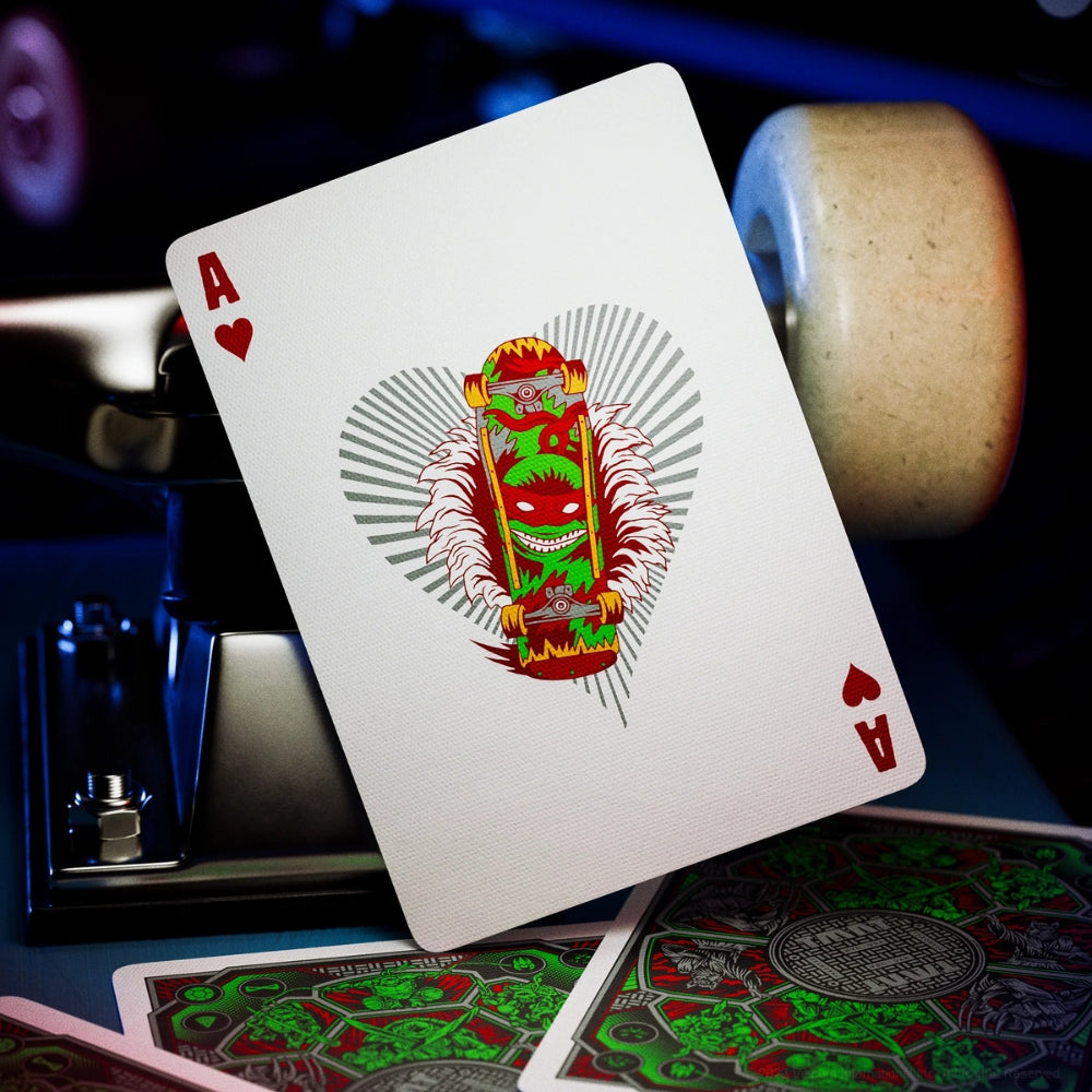 Ace of hearts playing card, from a teenage mutant ninja turtles deck, laying on top of a skateboard