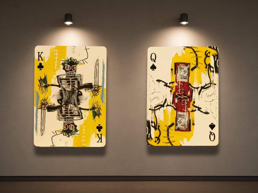 Art on playing cards featuring modern, abstract designs inspired by Jean-Michel Basquiat, with a King of Clubs and Queen of Spades displayed under spotlights.