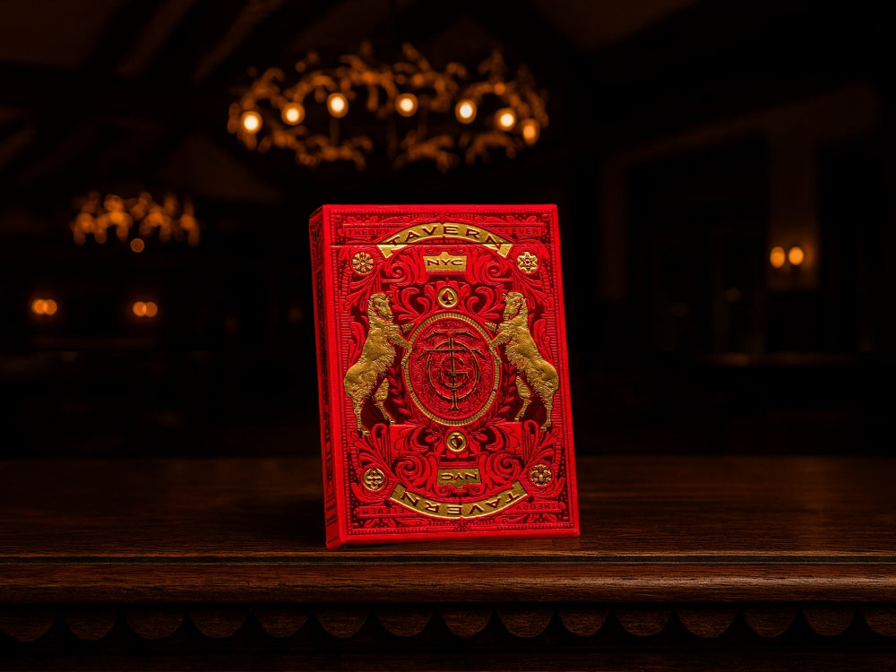 A luxurious red and gold deck of Theory11 playing cards displayed on a wooden table in a dimly lit room, representing the elegance and depth tied to the psychology of playing cards.