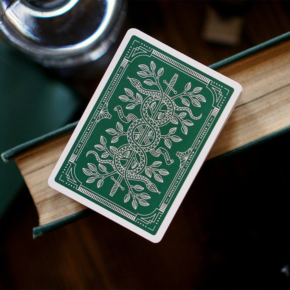 stack of green monarch playing cards, balanced on the edge of a hardback book