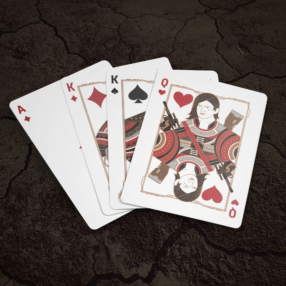 a fan of some face cards and an ace of diamonds from the mandalorian playing cards deck, all laying on a dry cracked surface