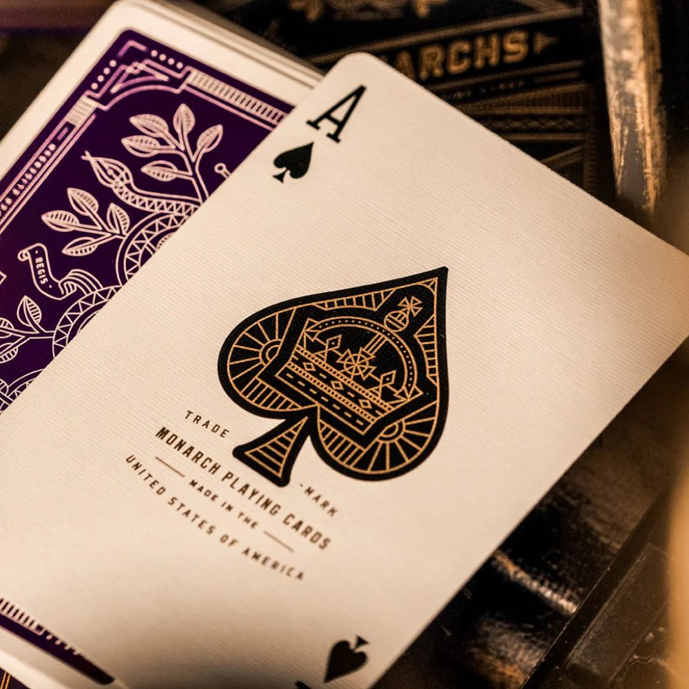 close up of the ace of spades laying some deck of facedown purple monarch playing cards