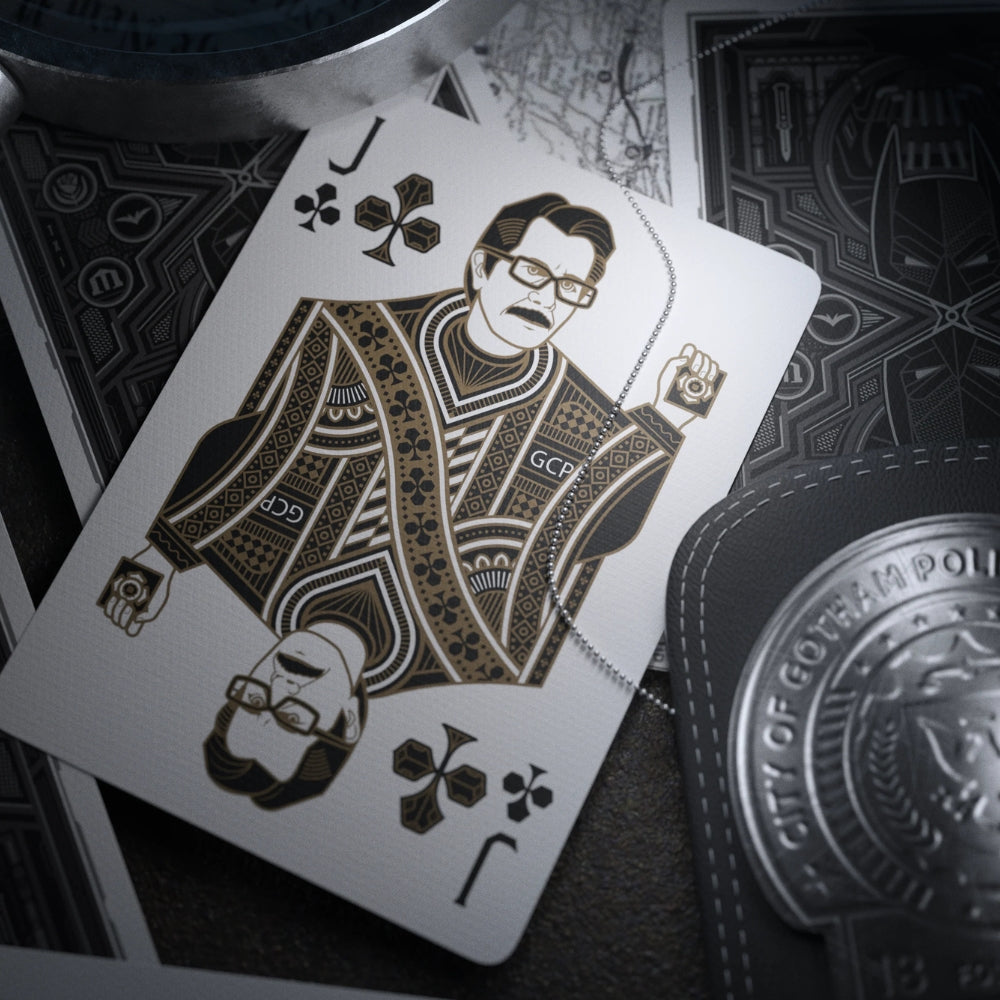 Jack of clubs card laying on some face down batman playing cards, with a Gotham police badge just in the shot