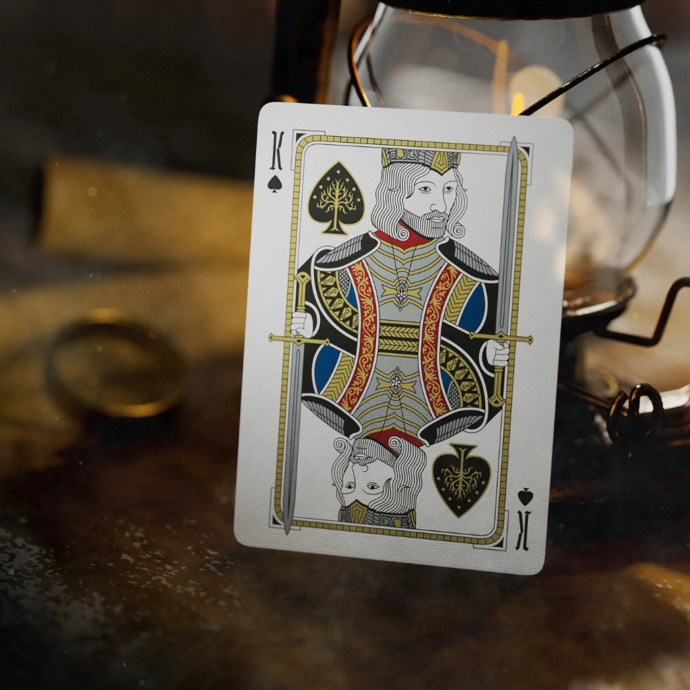 King of spades cards from a set of Lord of the rings playing cards, in the background we can see a lit lantern and a ring.