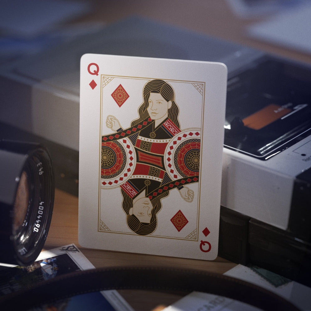 Queen of diamonds card from the spiderman deck of playing cards (theory11) - leaning on a deck with a old tape recorder, camera lens and some camera film negatives